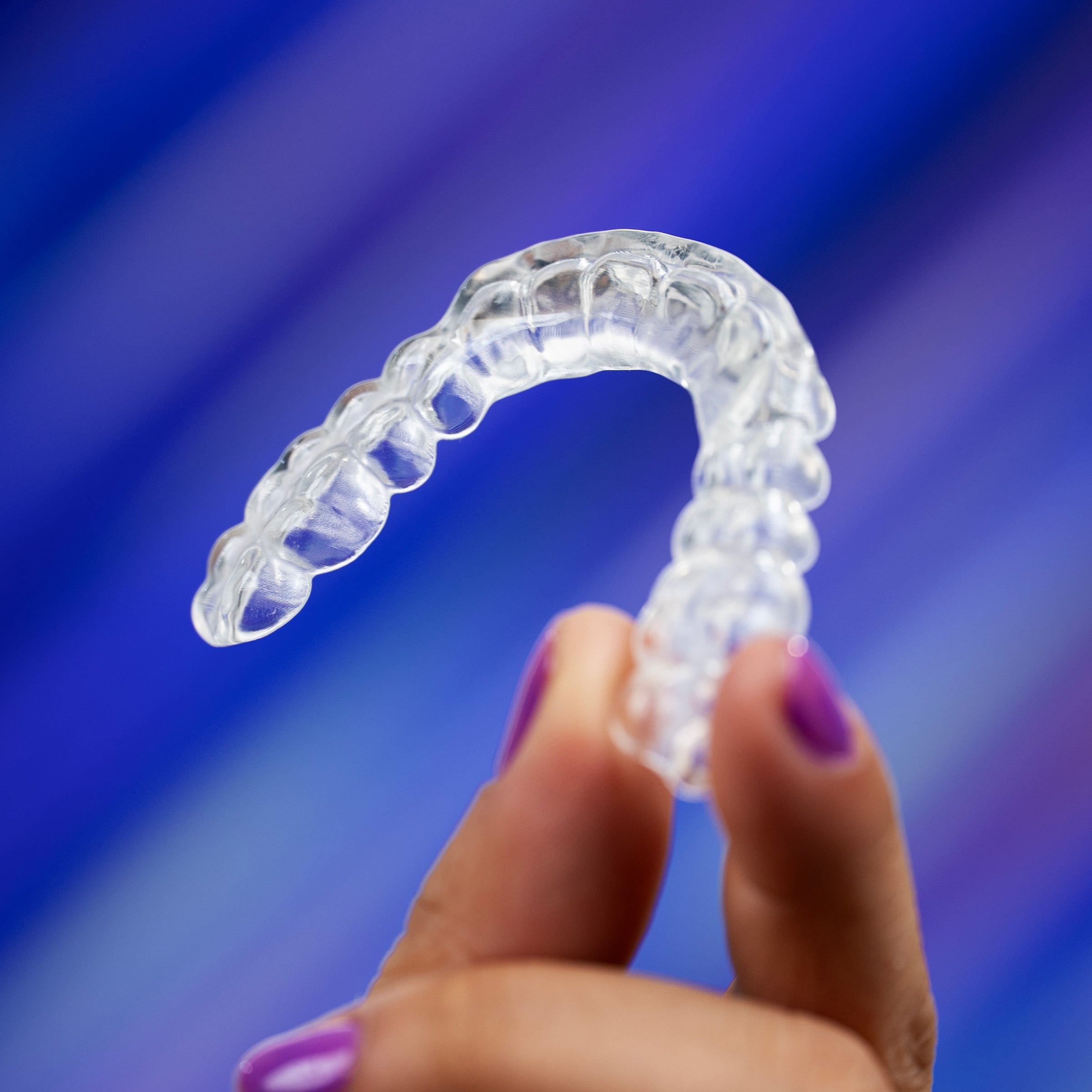 AccuGUARD deprogrammer from Great Lakes Dental Technologies held over abstract purple background