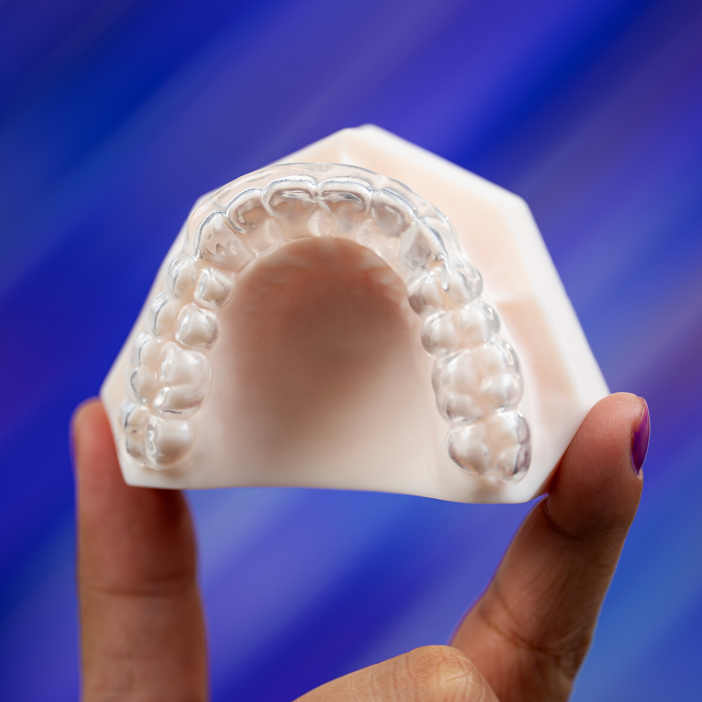 AccuGUARD deprogrammer from Great Lakes Dental Technologies held over abstract purple background